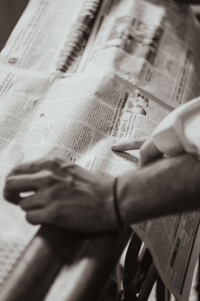 Close-up of hands pointing at a newspaper article with a retro feel in sepia tone.